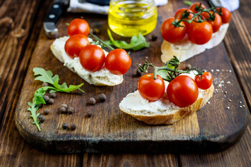 sandwiches with cheese and cherry tomatoes on a dark jar board on a wooden table close-up