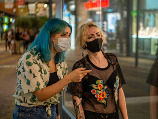 Shot of two women wearing medical masks talking to each other  - new normal
