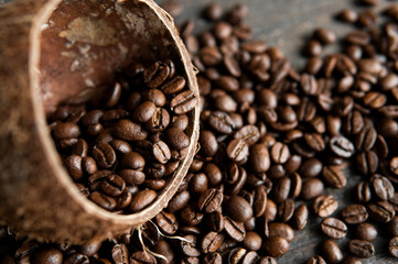 Roasted arabica coffee beans scattered on a wooden table from a coconut. Fresh coffee beans.