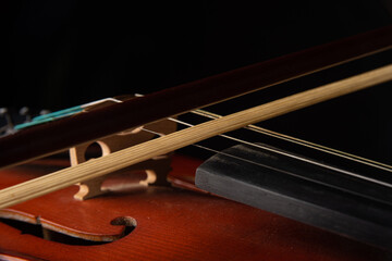 Details of an old and beautiful violin on a rustic wooden surface and black background, low key portrait, selective focus.