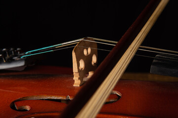 Naklejka na ściany i meble Details of an old and beautiful violin on a rustic wooden surface and black background, low key portrait, selective focus.