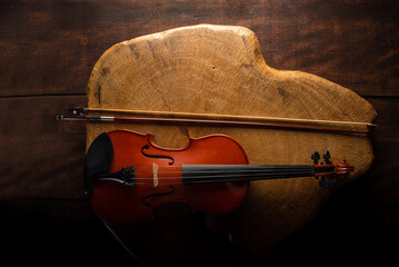 Old and beautiful violin on a rustic wooden surface and black background low key portrait,...