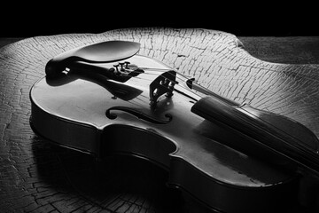 Details of an old and beautiful violin on a rustic wooden surface and black background, low key...
