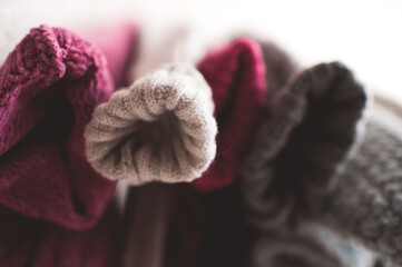 Knitted colorful clothes hang on rack indoors in shop. Season sale time. Selective focus.