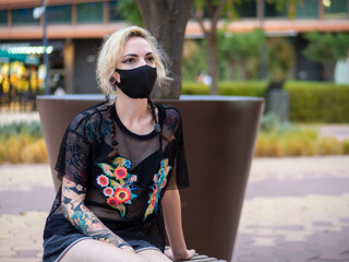 Woman wearing a medical mask sitting on a bench - new normal
