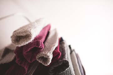 Knitted colorful clothes hang on rack indoors in shop. Season sale time. Selective focus.