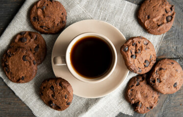 Coffee cup with cookies on wooden table background. Mug of black coffee with chocolate cookies. Fresh coffee beans.