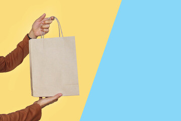 Hands give brown paper bag, Commercial concept for shopping sale offer or business offer with minimal colorful background and copy space for text and logo.