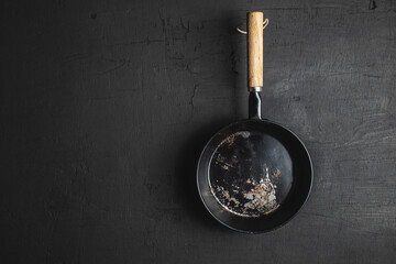 A pan for cooking on a black background - obrazy, fototapety, plakaty