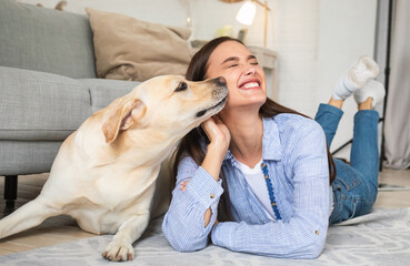 Young smiling woman with dog lying on floor