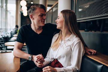 Cheerful couple holding hands in cafe