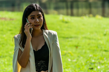 Asian Business Woman Talking with customer on mobile phone  in public park