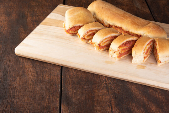 Homemade bread stuffed with ground mortadella and tomato sauce with black background. Low key image, selective focus.