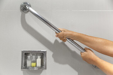 Senior woman holding on handrail for safety in bathroom