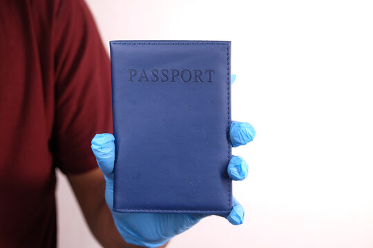 hand in blue surgical gloves holding passport in hand.