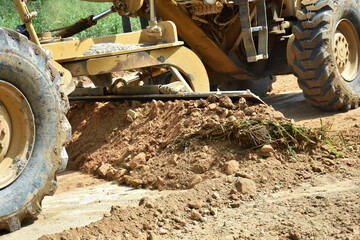A pile of soil with blade of motor grader machine work for clearing ground level before soil...