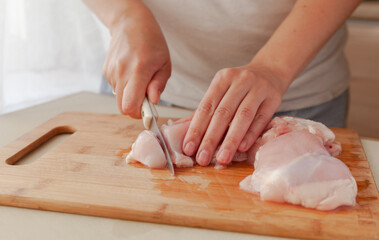 Obraz premium Slicing chicken fillet. Cooking fried chicken in a pan.