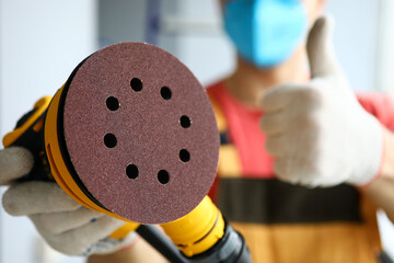 Sandpaper in hands of handyman in protective mask