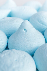 Fototapeta na wymiar A lot of fresh sweet meringues of gentle blue color, vertically background. Fluffy candies made with eggs and sugar, homemade delicacy, creamy treat, dessert, baking decor, pastry shop.