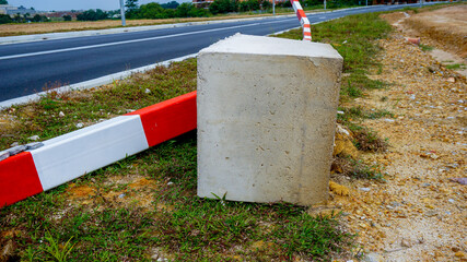 Red and white striped concrete road barrier lying on the road side
