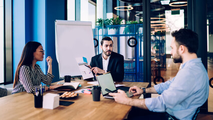 Multiracial colleagues discussing report during meeting in office