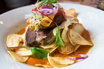 Delicious restaurant dish from Hungarian cuisine - beef steak cooked on medium rare roast, served with homemade potato chips, fresh vegetable salad and red wine sauce