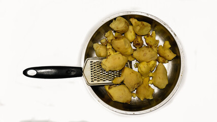 Peeled gingers kept in a steel plate and a hand held grater ready to be grated.