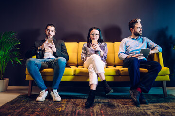 Diverse people obsessed with gadgets sitting on sofa