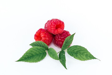 Ripe fresh natural raspberries with green leaves close-up on a white background