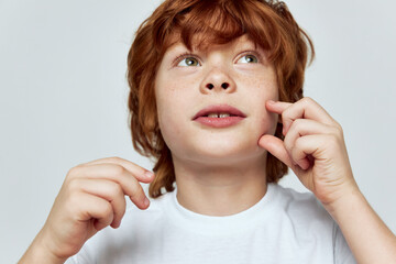 close-up redhead boy looking up hand near face cropped view 