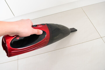 Red car vacuum cleaner, hand holding a car vacuum cleaner, cleaning the floor