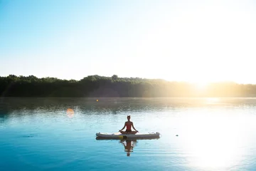 Foto op Canvas Woman meditating and practising yoga during sunrise in paddle board © Marko