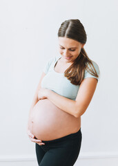 Young pregnant woman in sport wearing isolated on the white background