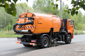 Big orange machine clears the asphalt with a sweeper near the curb