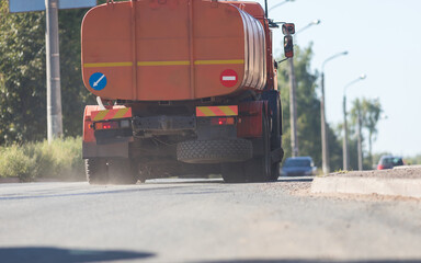 Big orange industrial truck riding on the road