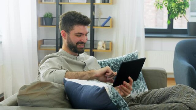technology, people and lifestyle concept - happy man with tablet pc computer at home