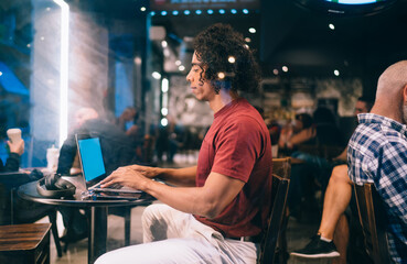 Focused black male student browsing laptop in cafe