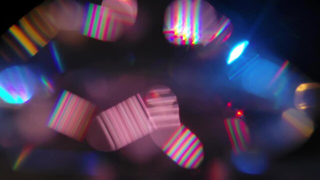 A Play Of Light Reflected In Multiple Facets Of A Precious Crystal. Refraction Of Light And Iridescent Highlights On A Black Background. Multicolored Bokeh Circles Background Close Up In Slow Motion.