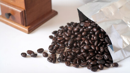 Grains of coffee in Foil bag on white table.