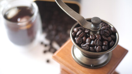 Coffee beans in Coffee grinder and blurred iced coffee in glass.