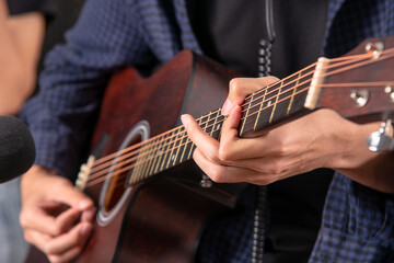 Fototapeta na wymiar Close up shot hands of guitarist perform with his acustic guitar