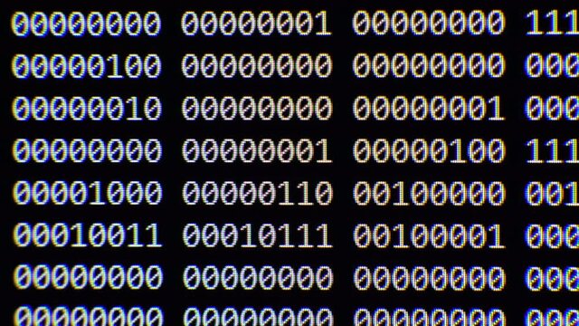 Close up on computer screen binary code on black background.