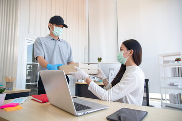 Obraz na płótnie Canvas Delivery man bring parcel to customer by wearing surgical mask and gloves in the office
