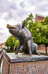 Sitting pig as a bronze statue on the canal bridge in the city of Wismar.