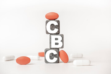 a group of white and red pills and cubes with the word CBC Complete blood count. on them, white background. Concept carehealth, treatment, therapy.