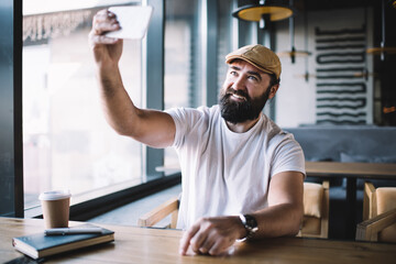 Bearded man taking selfie in cafe