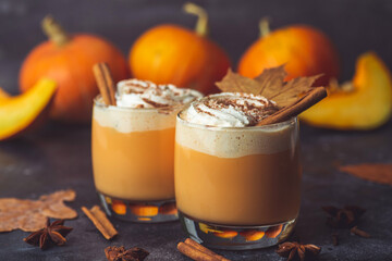 Pumpkin latte drink. Autumn coffee with spicy pumpkin flavor and cream on a dark background. Seasonal Fall Drinks for Halloween and Thanksgiving
