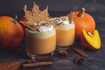 Pumpkin latte drink. Autumn coffee with spicy pumpkin flavor and cream on a dark background. Seasonal Fall Drinks for Halloween and Thanksgiving