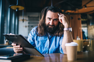 Long haired man leaning on hand with notebook in cafe