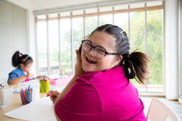 Young girls disabilities Or Down's syndrome learning about drawing shape and painting with bright smile for active learning and encouraging beside. Education and special child concept.
